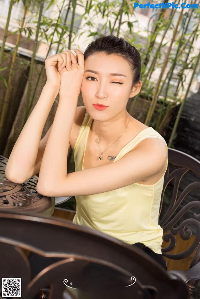 A woman sitting at a table with her hand on her chin.