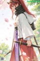 A woman with long red hair and cat ears holds a sword, dressed in traditional attire with cherry blossoms in the background.