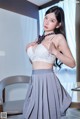 A woman in a white bra top and gray skirt posing for a picture.