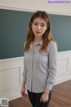 a woman standing in front of a blackboard wearing a blue shirt