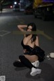A woman sitting on the ground in the middle of the street.