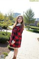 A young woman wearing a red and black plaid coat.