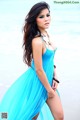 A woman in a blue dress standing on the beach.