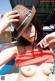 A woman in a straw hat is posing by a pool.