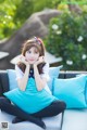 A woman sitting on a blue couch with her hand on her chin.