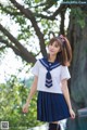 A woman in a sailor outfit posing by a pool.