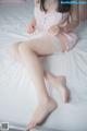 A woman in a pink lingerie sitting on a bed.