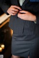 A woman in a business suit adjusting her tie.