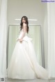 A woman in a wedding dress standing in front of a mirror.