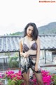 A woman in lingerie posing on a balcony with flowers.