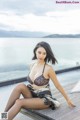 A woman sitting on a wooden dock next to a body of water.