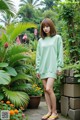 A woman in a green sweatshirt dress standing in a garden.