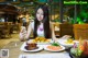 A woman sitting at a table with plates of food.