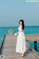 A woman in a white dress standing on a wooden pier.