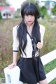 A woman with long black hair standing next to a white fence.