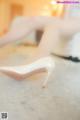 A close up of a woman's legs wearing white high heels.