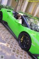 A woman sitting in the driver's seat of a green sports car.