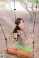 A woman in a green dress sitting on a swing.