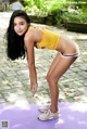 A woman in a yellow top and white shorts doing yoga.