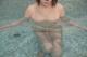 A woman in a swimming pool with her legs in the water.