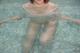 A woman in a white shirt is sitting in a pool.