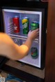 A person is opening a mini fridge with cans of beer.