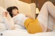 A woman laying on a bed in a white lace top and yellow skirt.