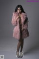 A woman in a pink fur coat posing for a picture.