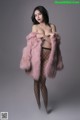 A woman in a pink fur coat posing for a picture.