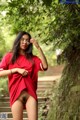 A woman in a red shirt is posing for the camera.