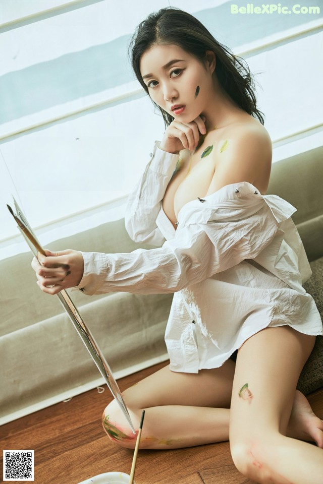 A woman sitting on a couch holding a paintbrush.