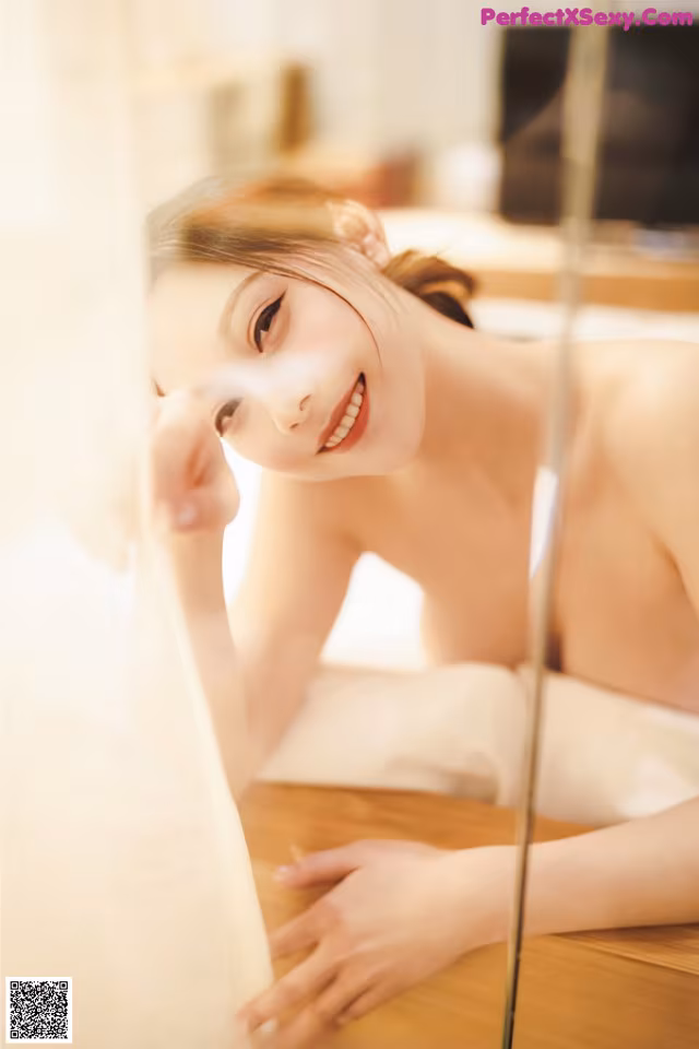 A woman laying on a bed looking at herself in the mirror.