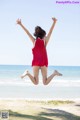 A woman jumping in the air on a beach.