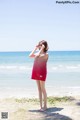 A woman in a red dress standing on a beach.