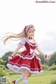 A woman in a red and white dress is walking in a field.