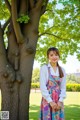 A woman standing in front of a tree in a park.